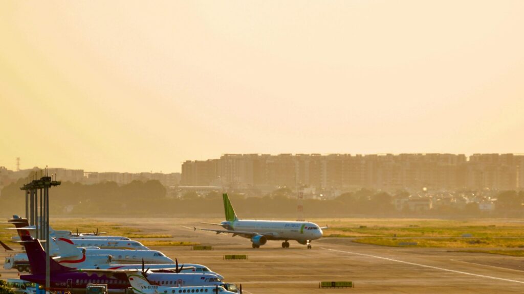 Airplanes parked on a runway during sunrise, capturing a busy airport scene.