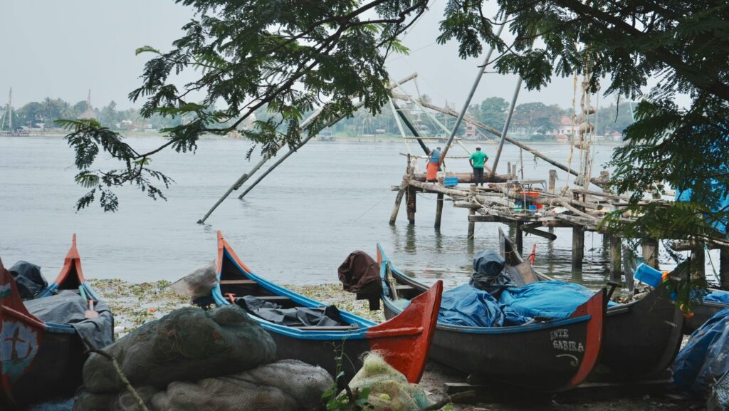 Top things to do in kochi.Traditional fishing boats and Chinese fishing nets by a river in India, capturing local culture.