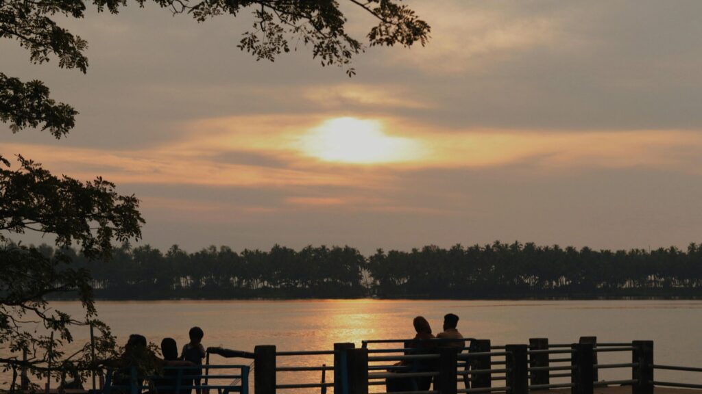A peaceful sunset scene with silhouettes by a lake, creating a warm and serene atmosphere.